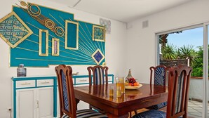 Ein Essbereich mit Holztisch und Stühlen, einer dekorativen Wand und Blick ins Freie.