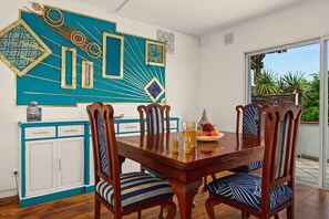 Un comedor con una mesa y sillas de madera, un muro decorativo y vistas al exterior.