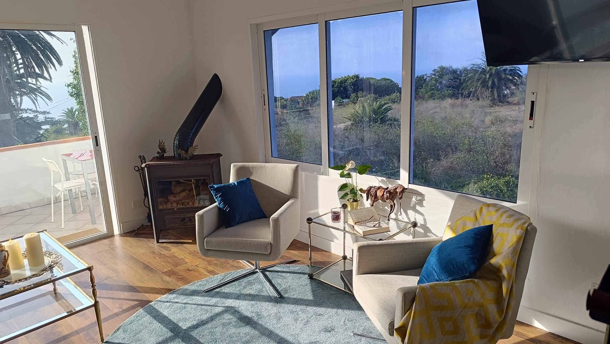Una sala de estar con chimenea, dos sillones, una mesa de centro y vistas al exterior.