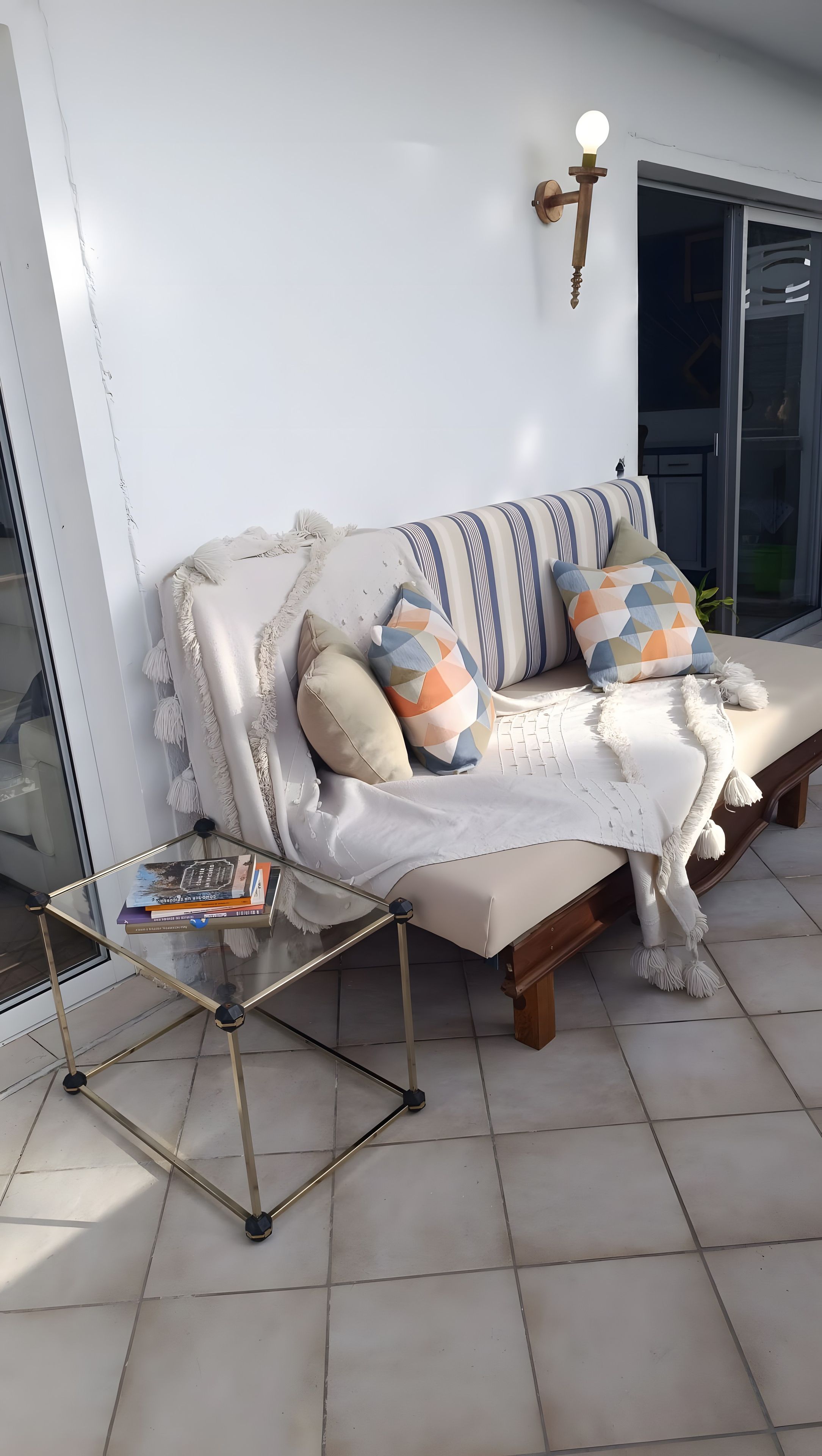 Ein Sofa mit Kissen, ein kleiner Tisch mit Büchern und eine Wandleuchte.