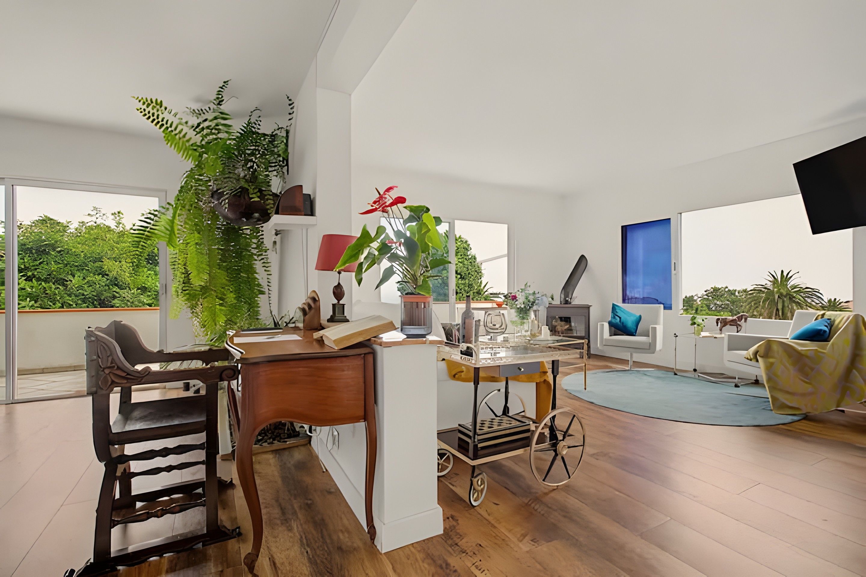 Amplia sala de estar con piso de madera, una mesa de comedor con sillas, un sofá y un televisor montado en la pared.