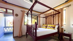 Una cama con dosel de madera, un edredón estampado y una mesita de noche con una lámpara.