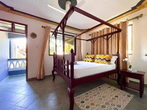 A four-poster bed with a wooden frame, a patterned bedspread, and a small bedside table with a lamp. - Spacious 6-bedroom villa in Diani with a swimming pool and access to the beach (Kwale County)