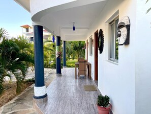 A covered outdoor area with a table and chairs, surrounded by a white wall with decorative elements and a potted plant. - Spacious 6-bedroom villa in Diani with a swimming pool and access to the beach (Kwale County)