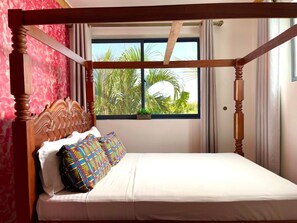 A four-poster bed with a window view of palm trees. - Spacious 6-bedroom villa in Diani with a swimming pool and access to the beach (Kwale County)