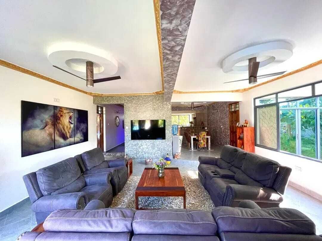 Ein geräumiges Wohnzimmer mit Kamin, Flachbildfernseher und großem Fenster.