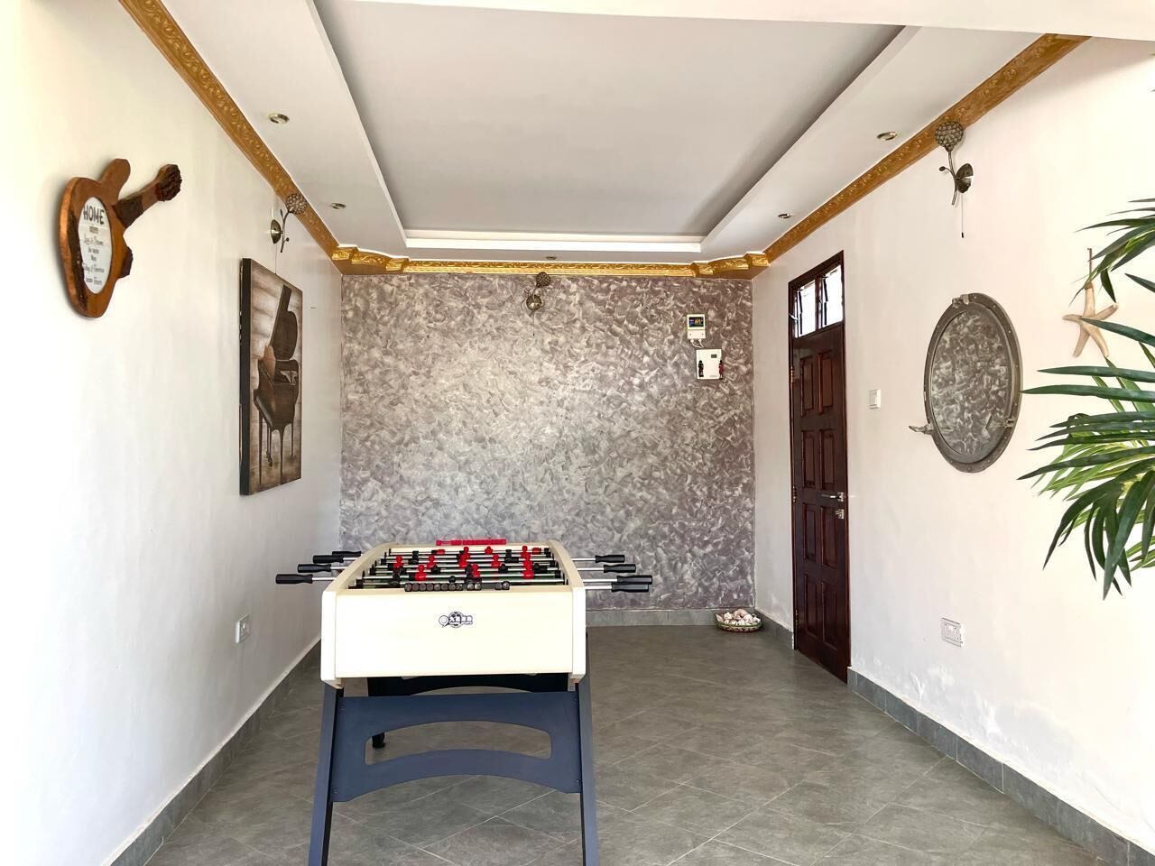 Ein Zimmer mit einem Kicker, einer Tür und einer Wandleuchte.