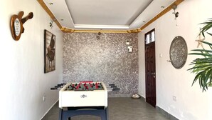 Una habitación con una mesa de fútbol de mesa, una puerta y un accesorio de luz instalado en la pared.