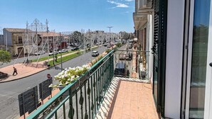 A balcony with a view of a street lined with buildings, a stop sign, and a pedestrian. - ETNERA (Trecastagni)