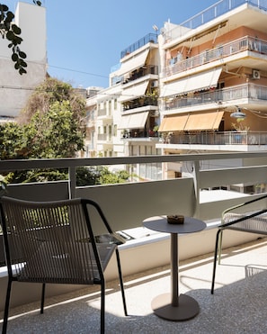 A balcony with a round table and two chairs, overlooking a multi-story building with balconies. - Thiseio Acropolis Residence by Fineline  (Athina)