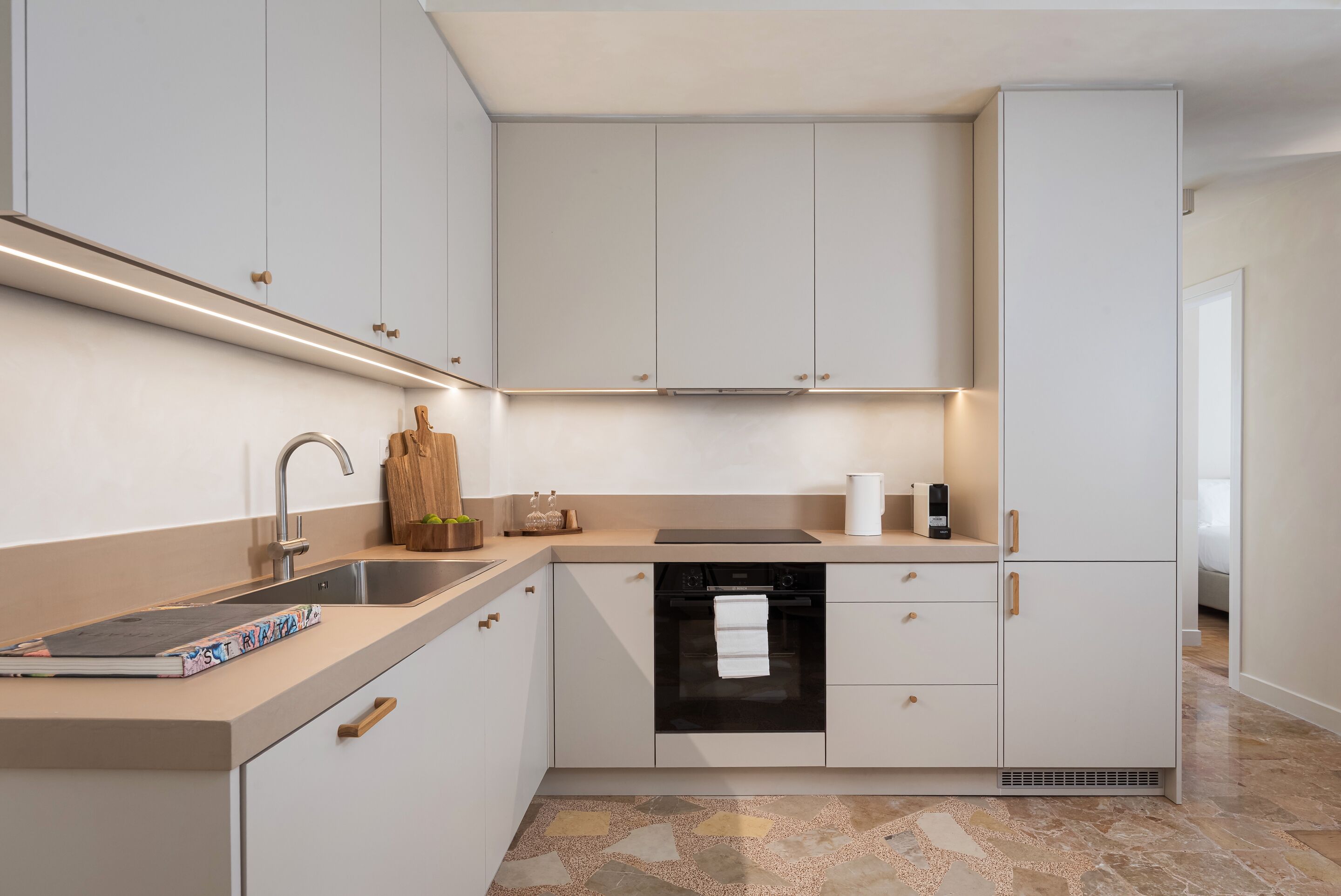 Una cocina moderna con lavavajillas integrado, un lavamanos y una encimera con tabla de cortar y un libro.