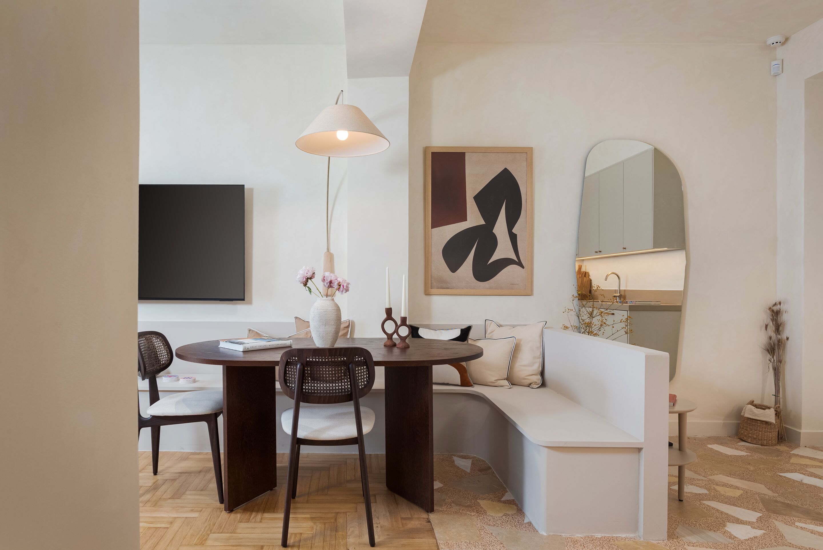 A modern living room with a dining area, a sofa, a TV, and a large abstract painting.
