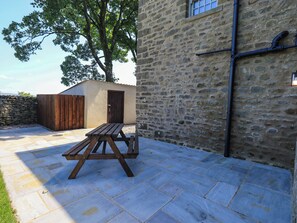 A stone building with a wooden door, a picnic table, and a stone wall.