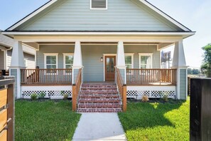 A two-story house with a front porch, a brick staircase, and a small front yard. - Designer Home Near Downtown w/Patio+Board games (Houston)