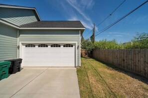 A garage with a white door, a concrete driveway, and a wooden fence in the background.