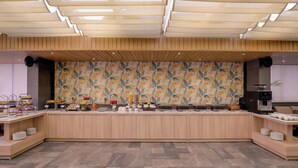 Un área de cocina moderna con una encimera larga, varios electrodomésticos y un panel decorativo con motivos florales.