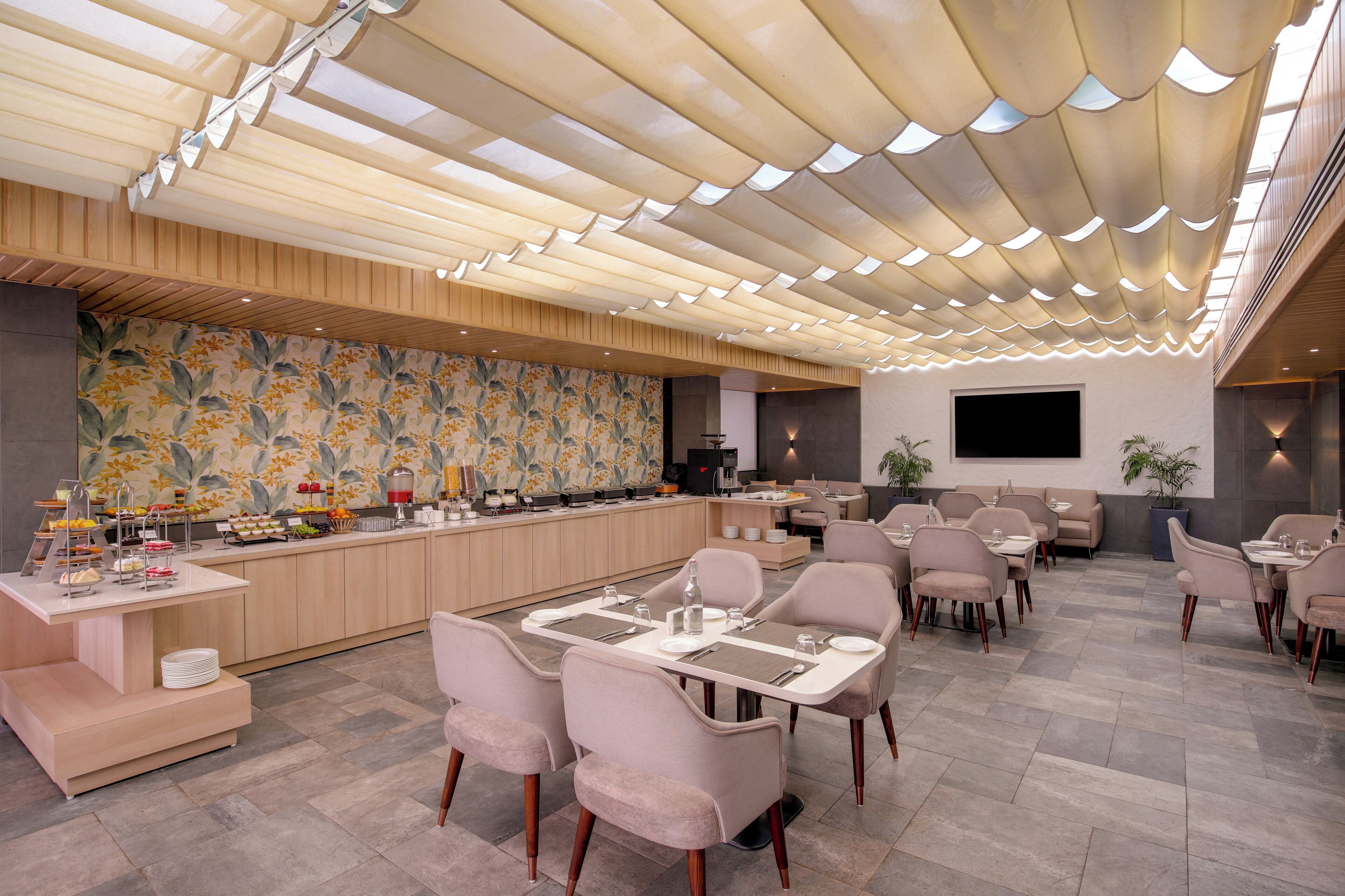 Un ristorante moderno con un lungo bancone, posti a sedere imbottiti e una parete decorativa.
