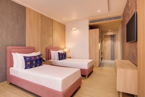 Habitación de hotel con dos camas, un escritorio y televisión.