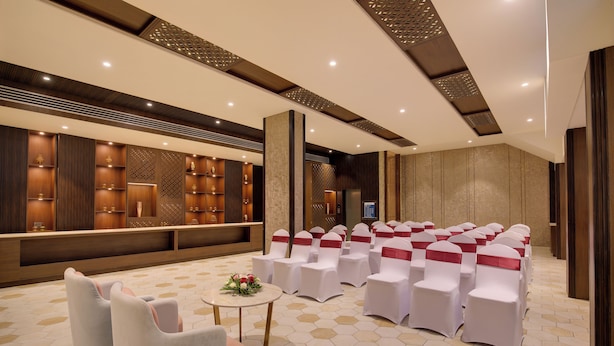 Un salón de conferencias con sillas blancas, una mesa de recepción y un suelo con diseño hexagonal.