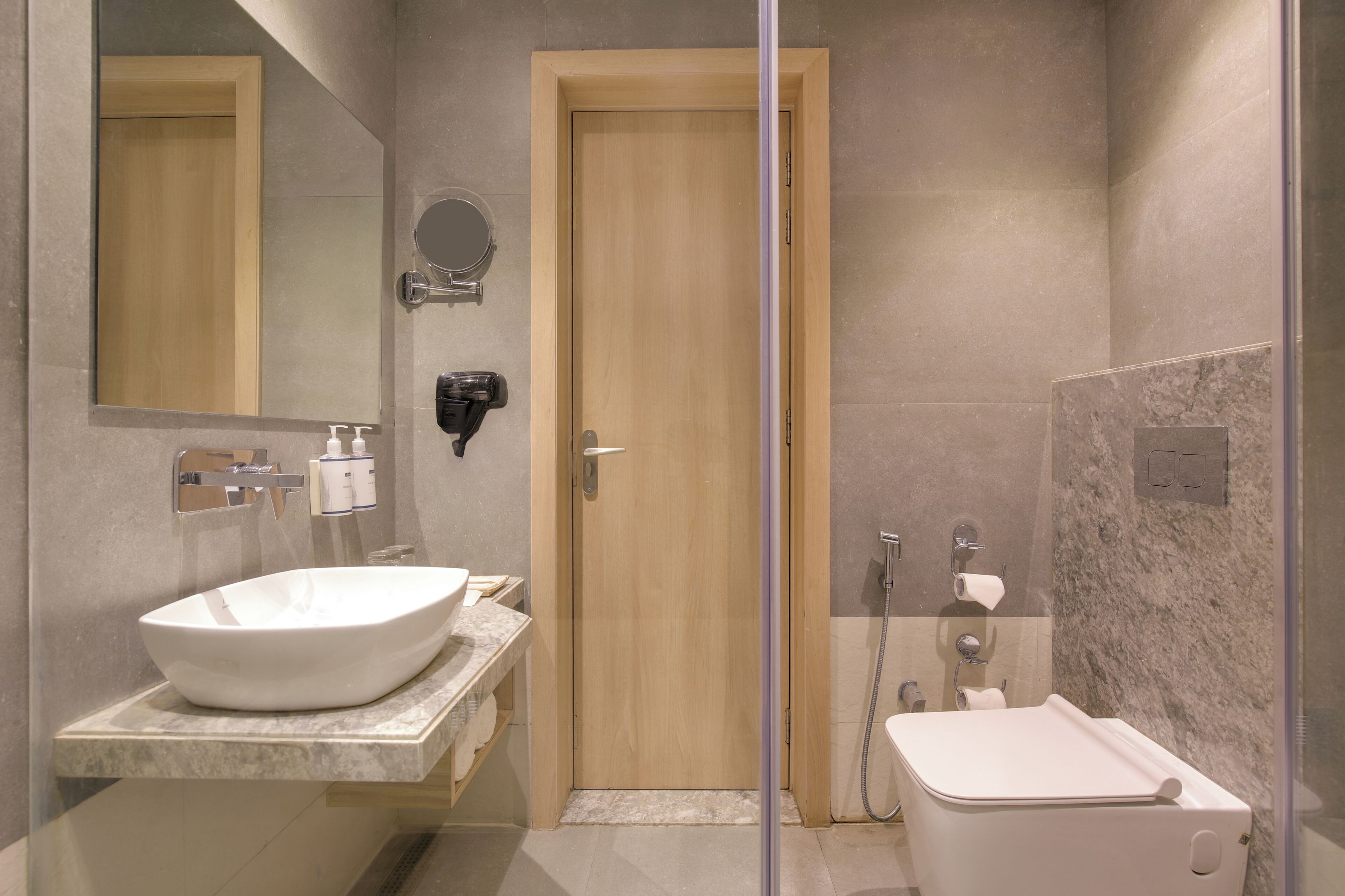 Un baño moderno con un lavamanos grande, un espejo, un inodoro y una zona de ducha.