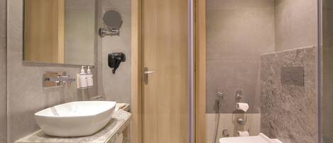Un baño moderno con un lavamanos grande, un espejo, un inodoro y una zona de ducha.