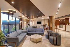 A modern hotel lobby with a seating area, a round table, and a kitchen in the background. - Keys Lite by Lemon Tree Hotels Ajmer (Ajmer)