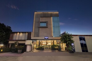Un hotel con fachada moderna, entrada visible y un letrero que indica un restaurante.
