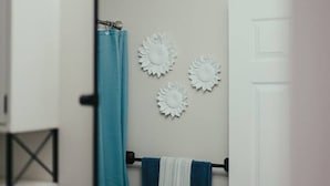 A bathroom with a mirror, a towel rack with towels, a shower curtain, and wall-mounted decorative items. - Beach Town Vibes • Relax & Unwind (Sylvan Lake)