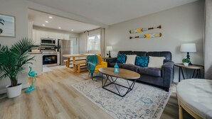 A modern living room with a sofa, coffee table, and a dining area with a table and chairs. - Beach Town Vibes • Relax & Unwind (Sylvan Lake)