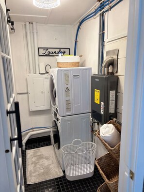 Un espace buanderie équipé d’un lave-linge, d’un sèche-linge et de paniers à linge empilés.