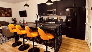 Una cocina moderna con gabinetes negros, una isla central con taburetes de bar, un microondas y un refrigerador.
