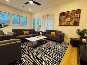 Ein Wohnzimmer mit einer Sofagarnitur, einem Couchtisch, einem gemusterten Teppich und einem Wandbild.