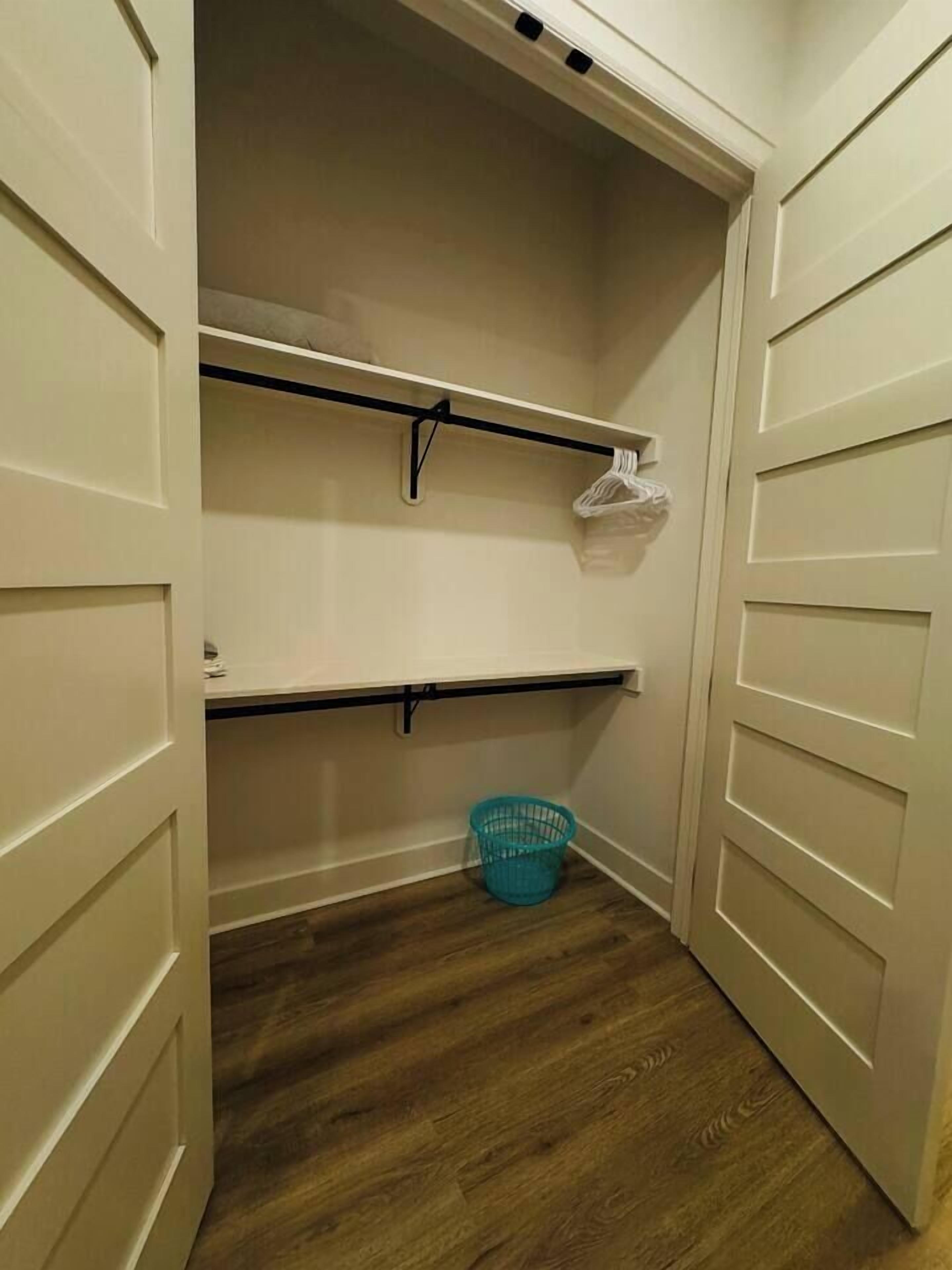 Ein Schrank mit geöffneten Türen, Holzboden und einem blauen Korb.