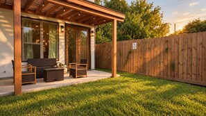 Eine überdachte Terrasse mit Gartenmöbeln, einem Holzzaun und einem Rasen.