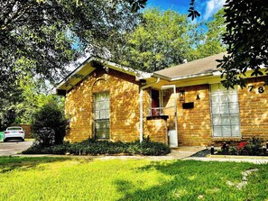 A two-story brick house with a front porch, a garage, and a well-maintained lawn. - Houston 2BR Stay | Near NRG, & Downtown | Coffee (Houston)
