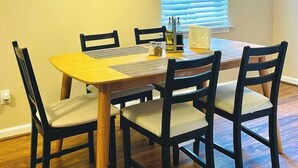 Ein Essbereich mit einem Holztisch, vier Stühlen und Pendelleuchten.