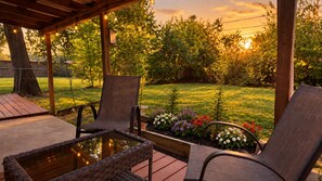 Eine Terrasse im Freien mit Tisch und Stühlen, umgeben von einem Garten mit verschiedenen Pflanzen und Blumen.