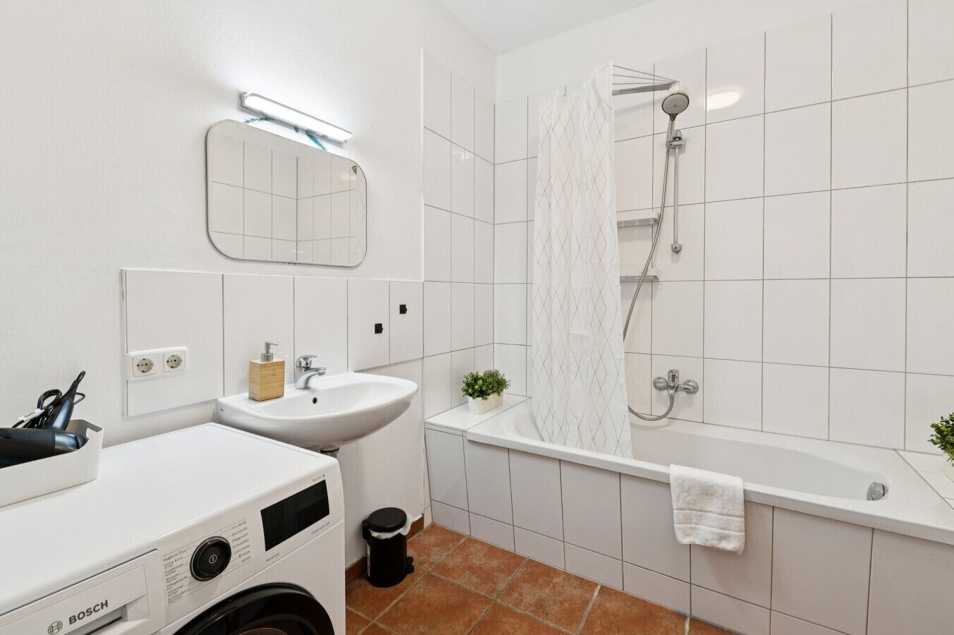 Un baño moderno con lavadora Bosch, un lavamanos, una ducha y un espejo.