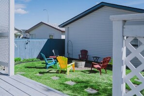 Ein Garten mit einer Holzterrasse, einem blauen Zaun und mehreren Adirondack-Stühlen.