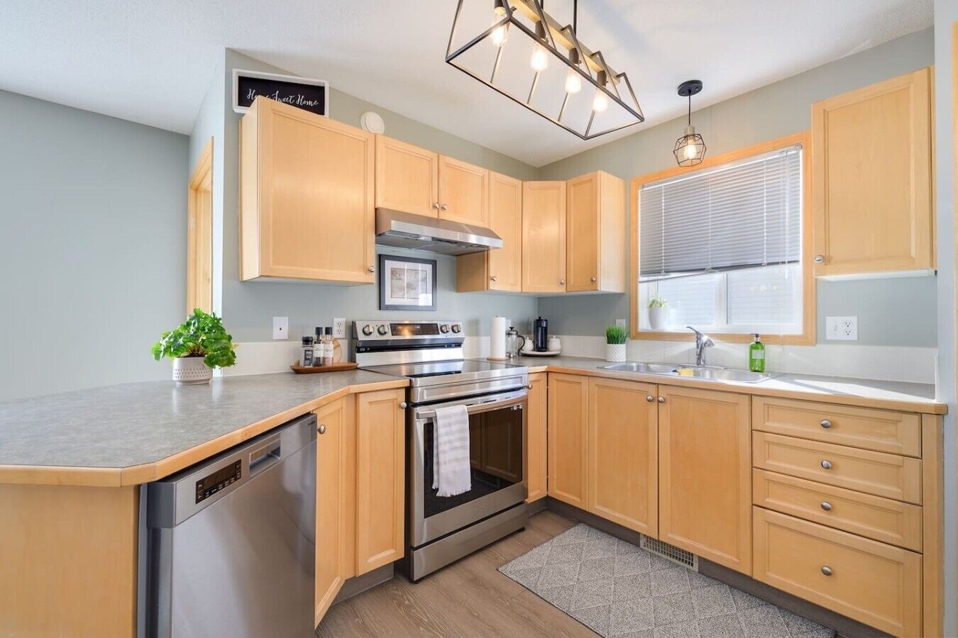 A modern kitchen with wooden cabinets, stainless steel appliances, and a built-in dishwasher.