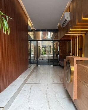 Un interior modern amb una taquilla d'entrada, una paret de fusta i una porta de vidre que dona a una zona exterior.