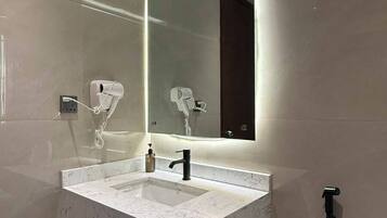 Une salle de bain moderne avec un lavabo en marbre, un grand miroir et une douchette à main.