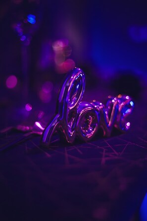 A metallic object with a reflective surface, possibly a sculpture, in a dimly lit environment with bokeh light effects.