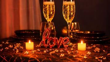 A table set with two champagne glasses, a lit candle, and a decorative 'love' sign.