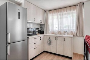 A compact kitchen with a stainless steel refrigerator, a microwave, and a sink. - Charming 1-Bedroom Garden Apartment Near Glyfada Center & Beach (Glyfada)