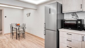 Eine moderne Küche mit einem Edelstahl-Kühlschrank, einer Mikrowelle und Holzschränken.