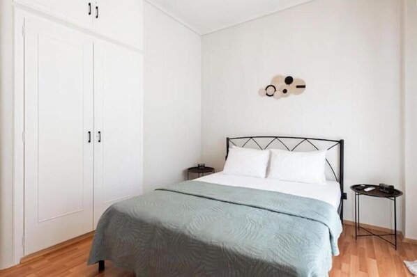 Una camera da letto con un letto, un armadio, un comodino e un elemento decorativo a parete.