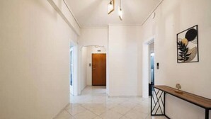 Un corridoio con una panca in legno, una porta in fondo e un'opera d'arte appesa al muro.