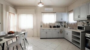Una cucina moderna con mobili bianchi, un tavolo da pranzo con sedie e un forno a microonde.