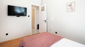 Una camera da letto con un letto, una televisione, una porta e un quadro appeso al muro.